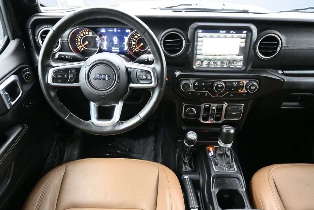 Cockpit of a used 2022 Jeep Wrangler with touchscreen and saddle leather trim