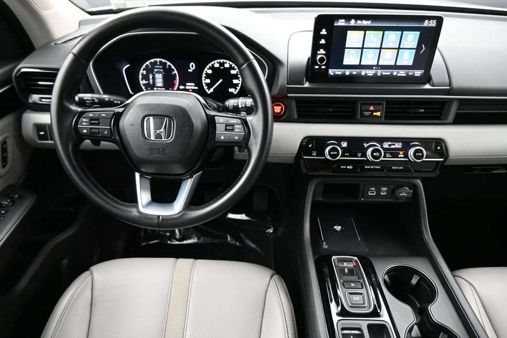 Cockpit and dashboard of a used 2023 Honda Pilot with touchscreen and light leather trim