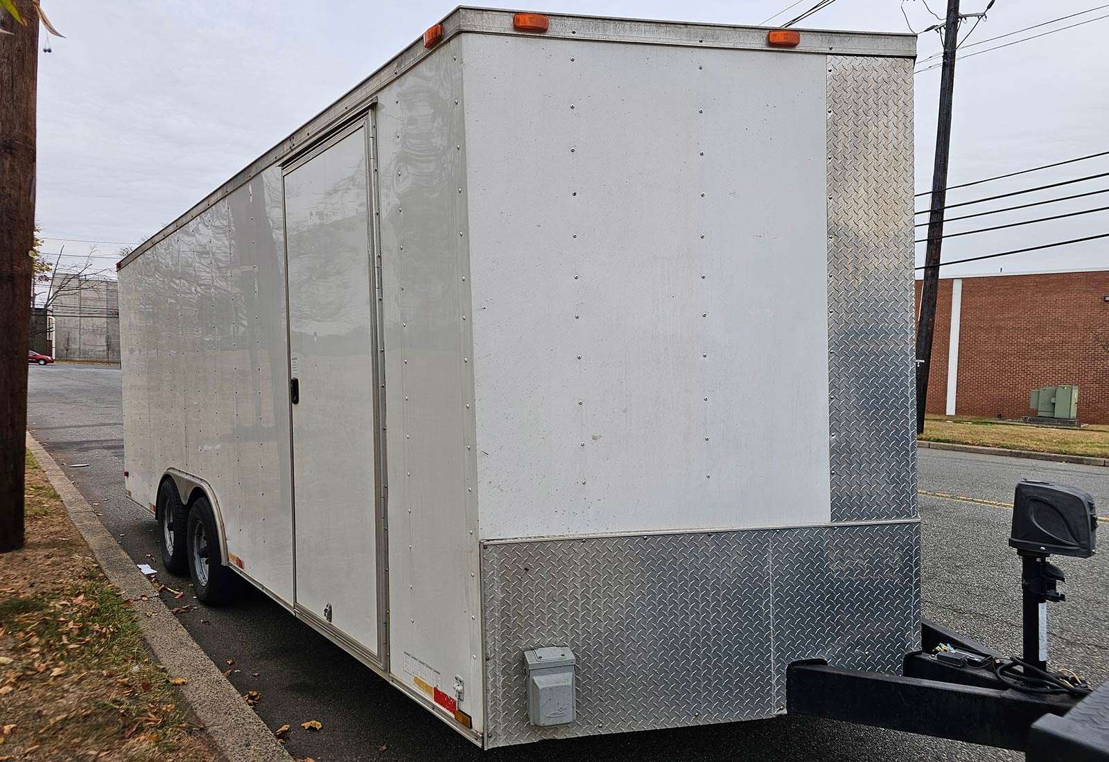 An enclosed trailer parked by the curb.