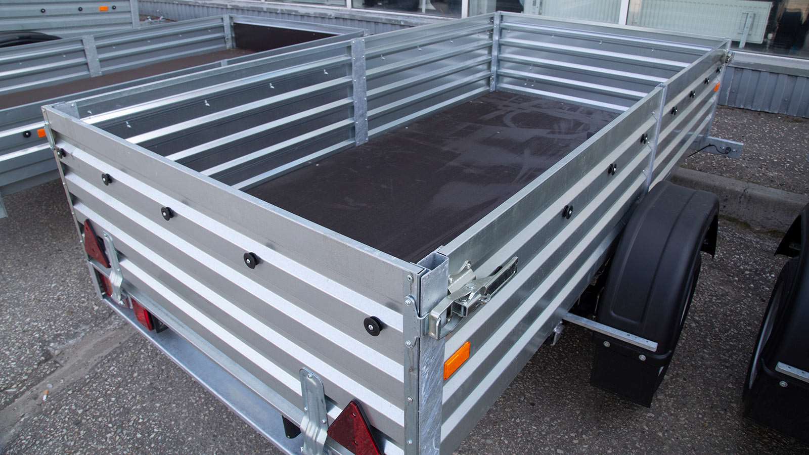 A car hauler trailer in front of a building.