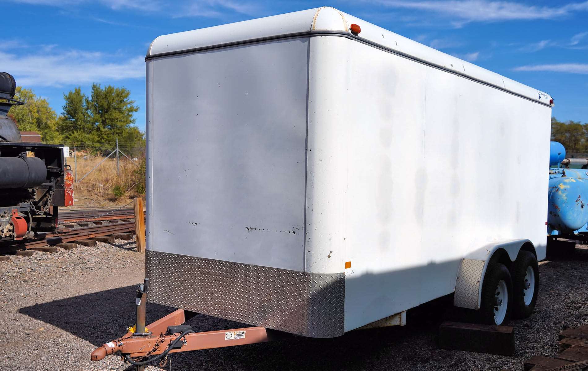 A white enclosed box trailer, currently untethered.
