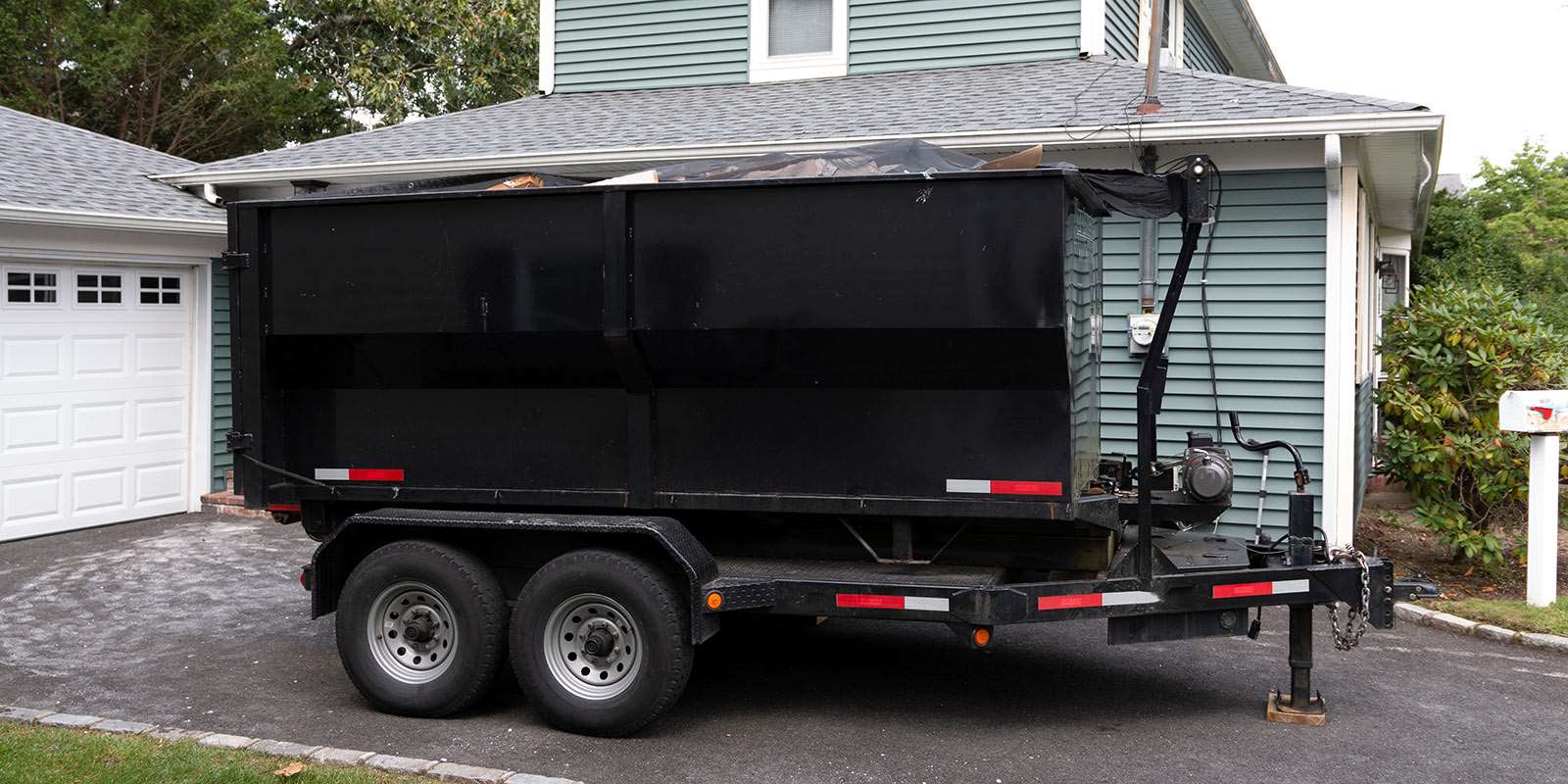 A black dump trailer parked in a driveway.