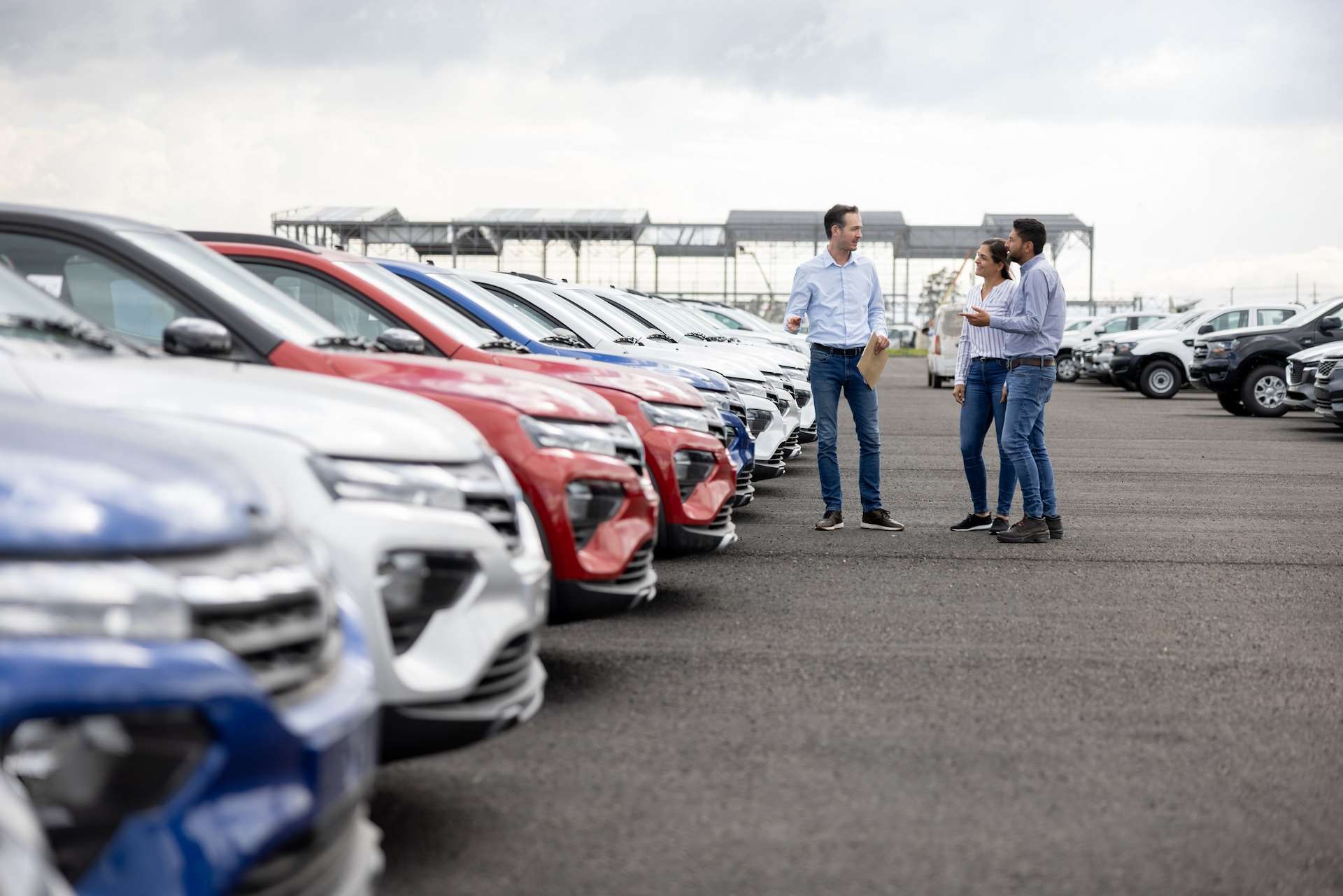 man showing couple around a dealership while they're looking at buying a car