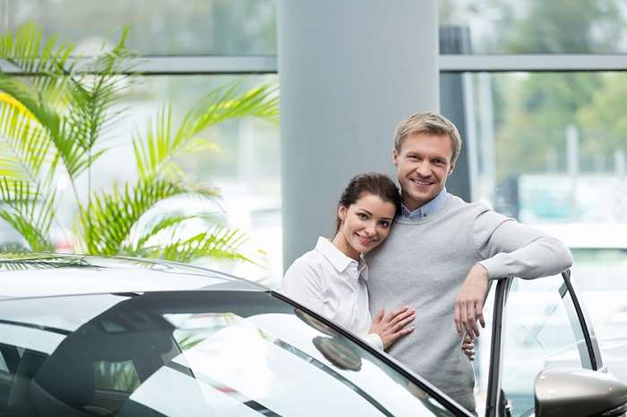 Happy couple standing by a vehicle